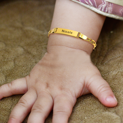 A gold plated personalized name bracelet on a baby's wrist