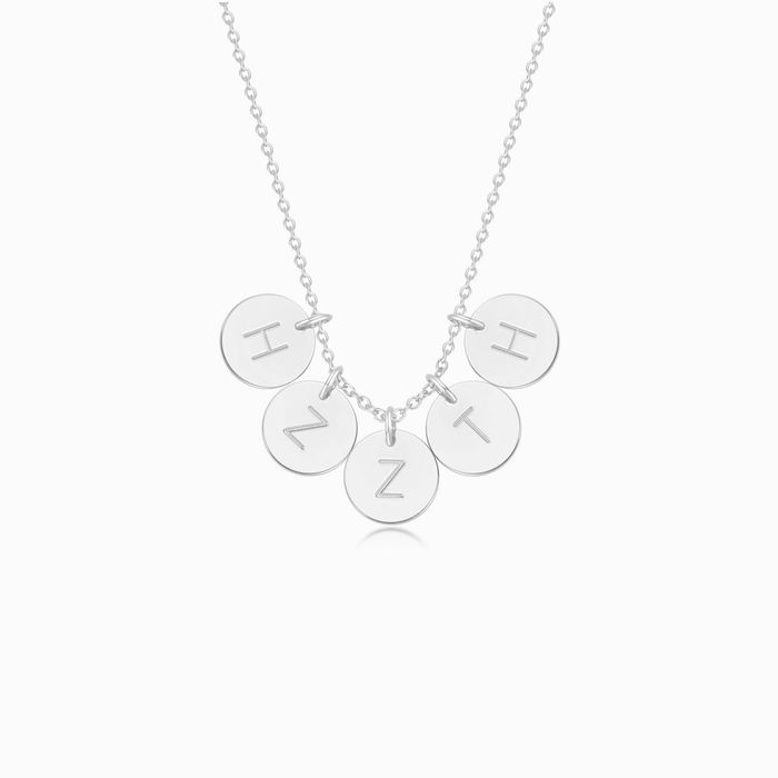 A silver necklace with five personalized initial discs on a white background