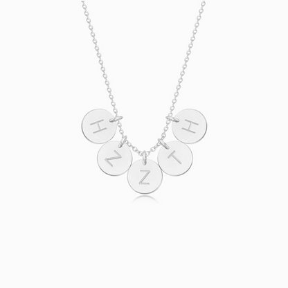 A silver necklace with five personalized initial discs on a white background