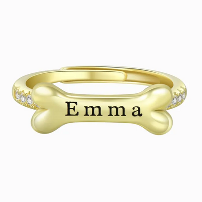 A gold dog bone ring design with personalized name on "Emma" on a white background.