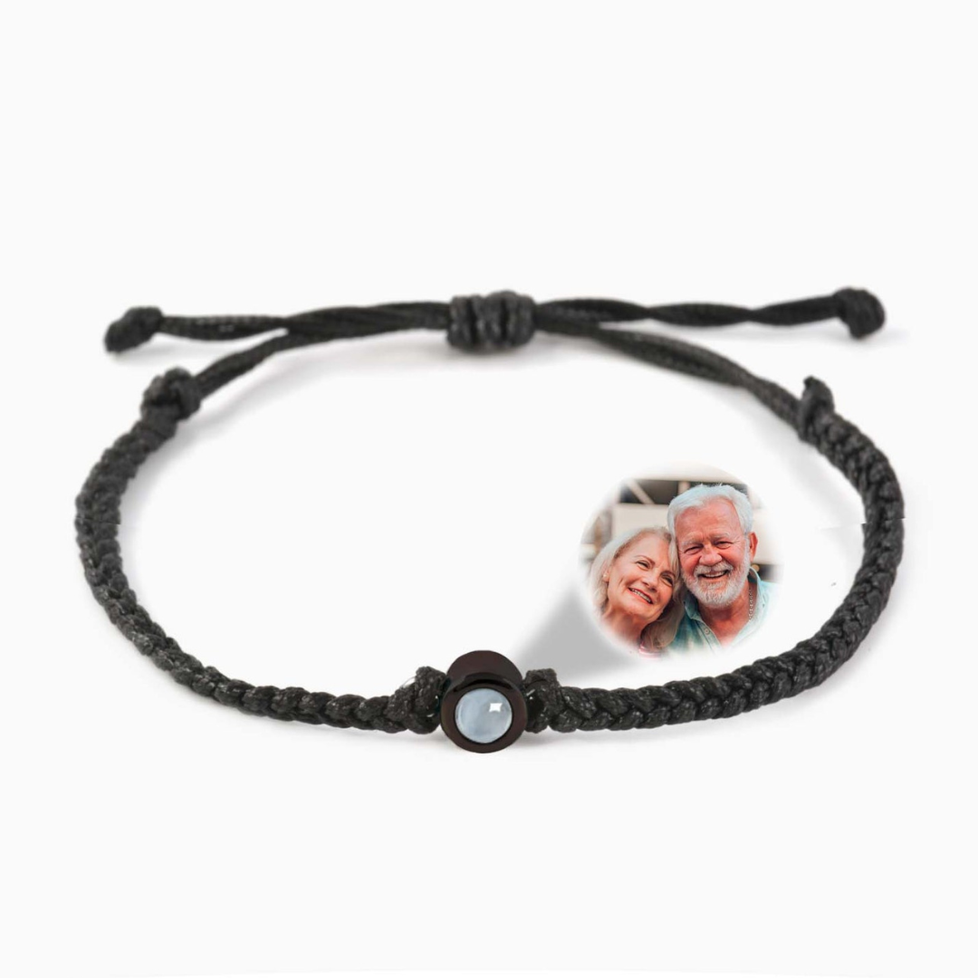 A black braided leather bracelet featuring a black circular pendant designed to project an image in a white background