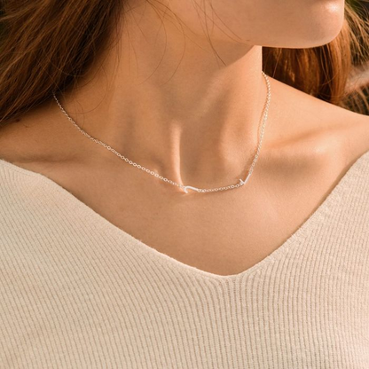 A silver personalized letter necklace on a woman's neck