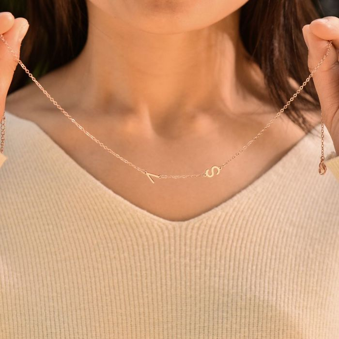 A rose gold personalized letter necklace on a woman