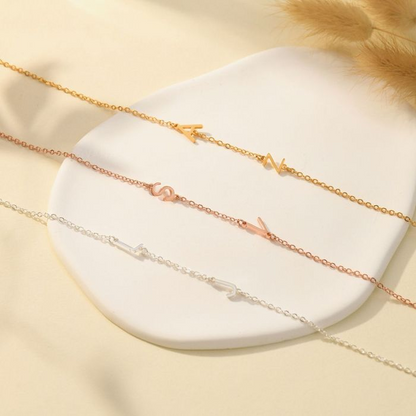 Gold, rose gold, and silver personalized letter necklaces on a white disc and floral background