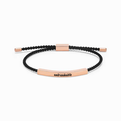 black rope with rose gold bar with "unbreakable" text engraving on a white background