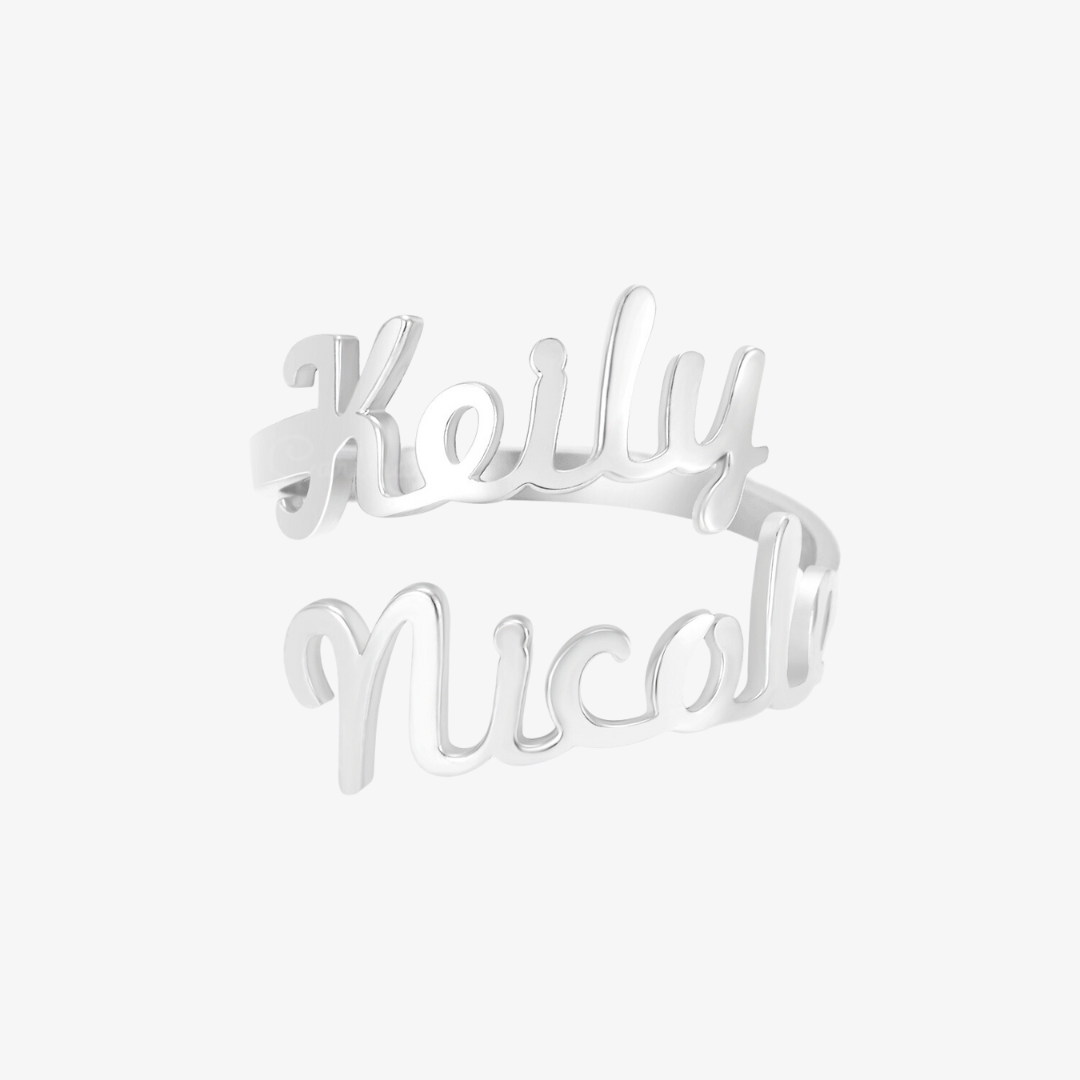 A silver ring featuring two names, "Keily" and "Nicole," elegantly written in a cursive font. The names wrap around the finger, forming the band of the ring in a personalized, stylish design.