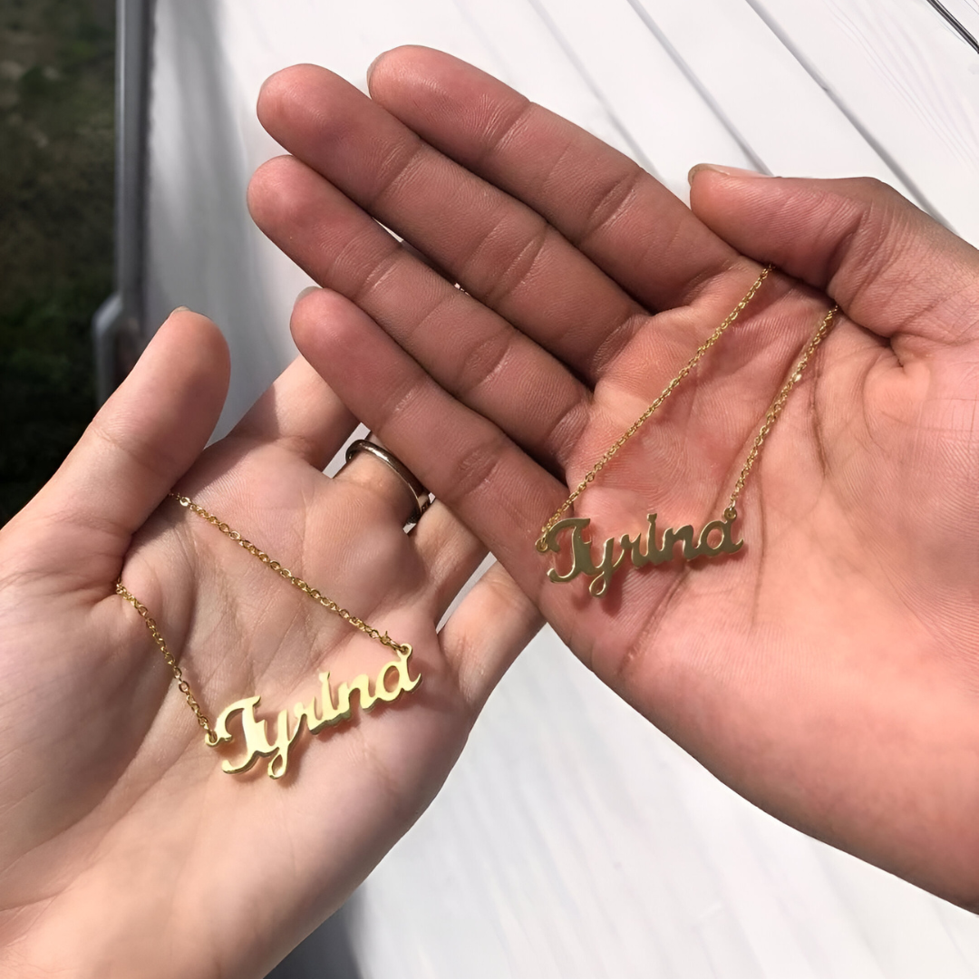 Gold chain necklaces with a customized name pendant being held by two models