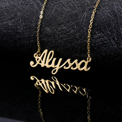 A gold chain necklace with a customized name pendant with a black background