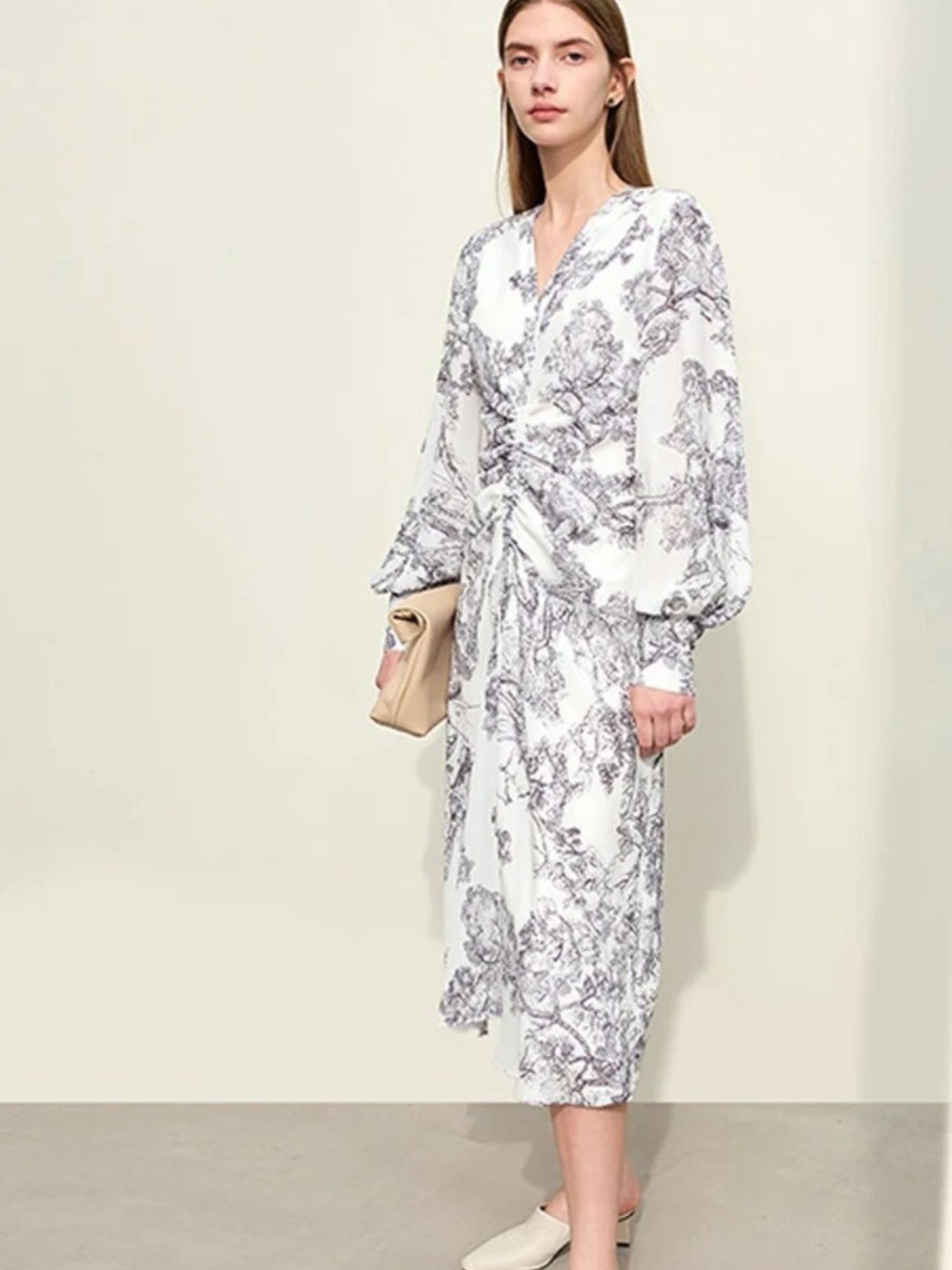 Woman wearing a white floral dress against a plain background